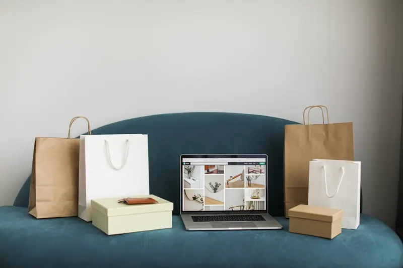 Laptop showing an online store, surrounded by shopping bags and gift boxes