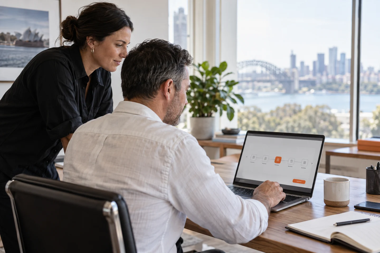 AI-generated photo showing A Sydney business owner approving the next step of an AI agent workflow on his laptop while his operations manager looks on