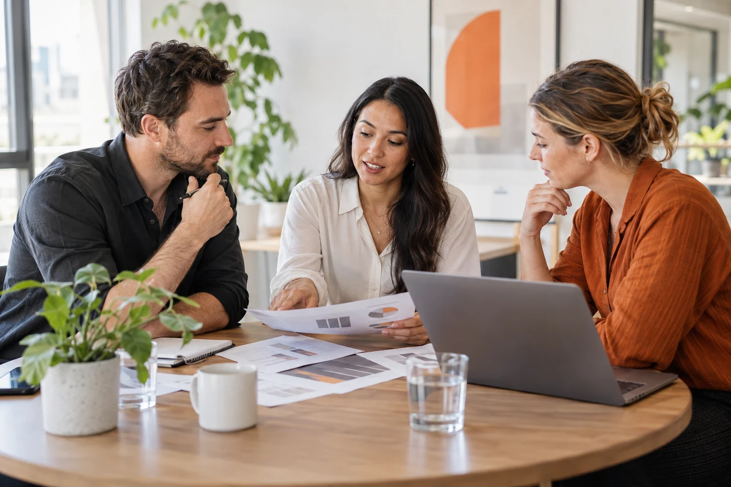 AI-generated photo showing Three colleagues at a round table talking through printed pilot results for a new AI tool