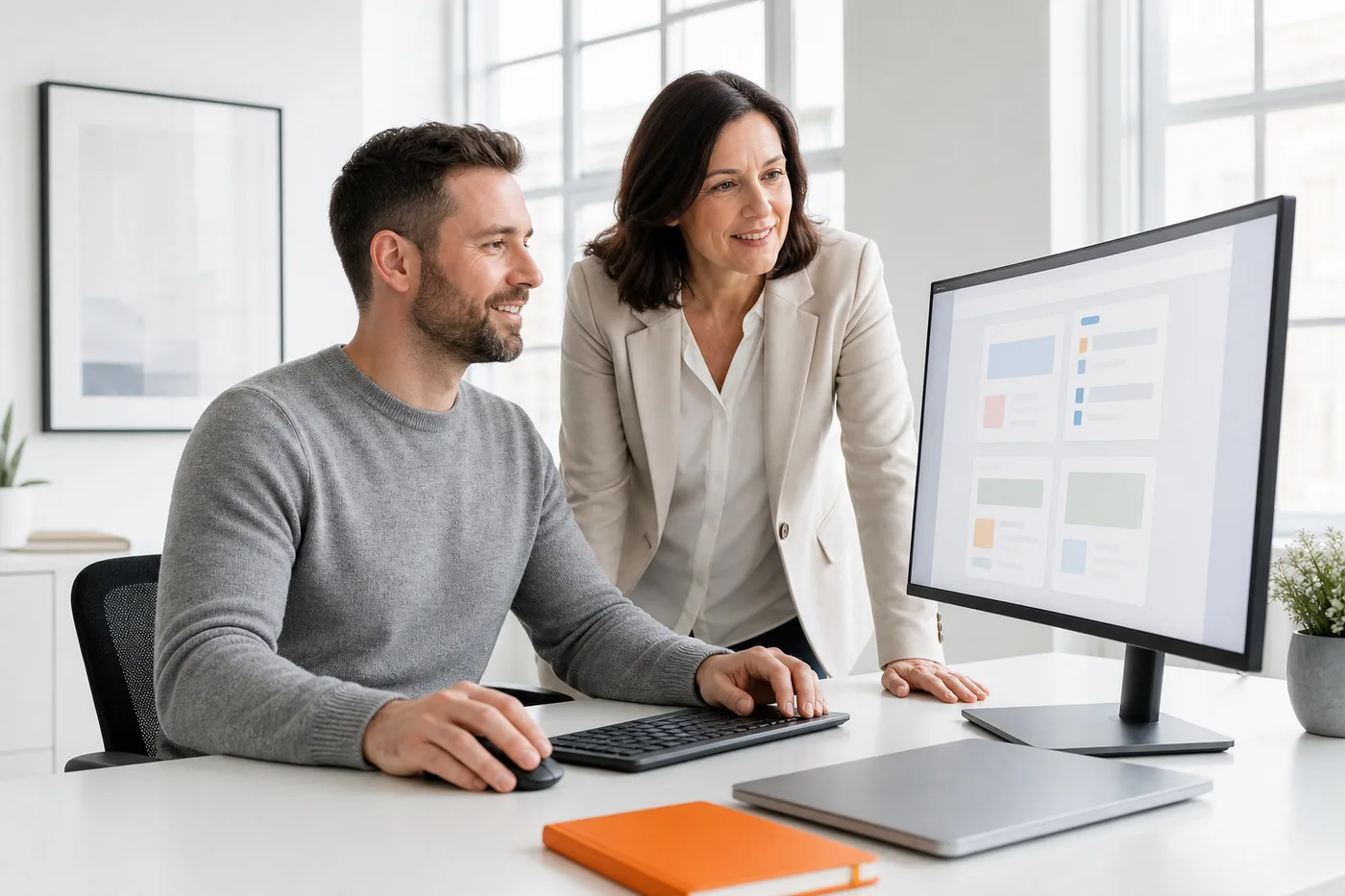 A FactoryJet developer and a UK business owner reviewing a custom internal AI tool on a large monitor in a bright office