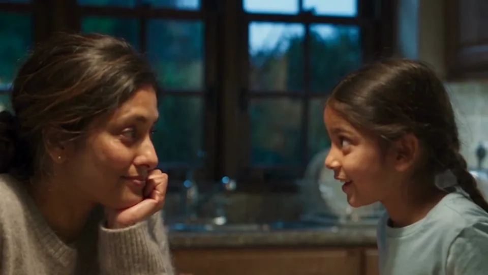 AI-generated still from our film: a mother laughs with her young daughter at the kitchen table at dinner.